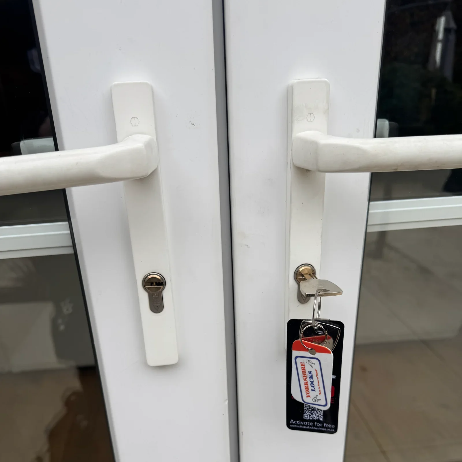Close-up of UPVC door handles with a key tag hanging from the lock.